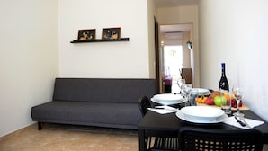 A dining area with a sofa, a table set for two, and a fruit basket. - Rodon Loutra (Kassandra)