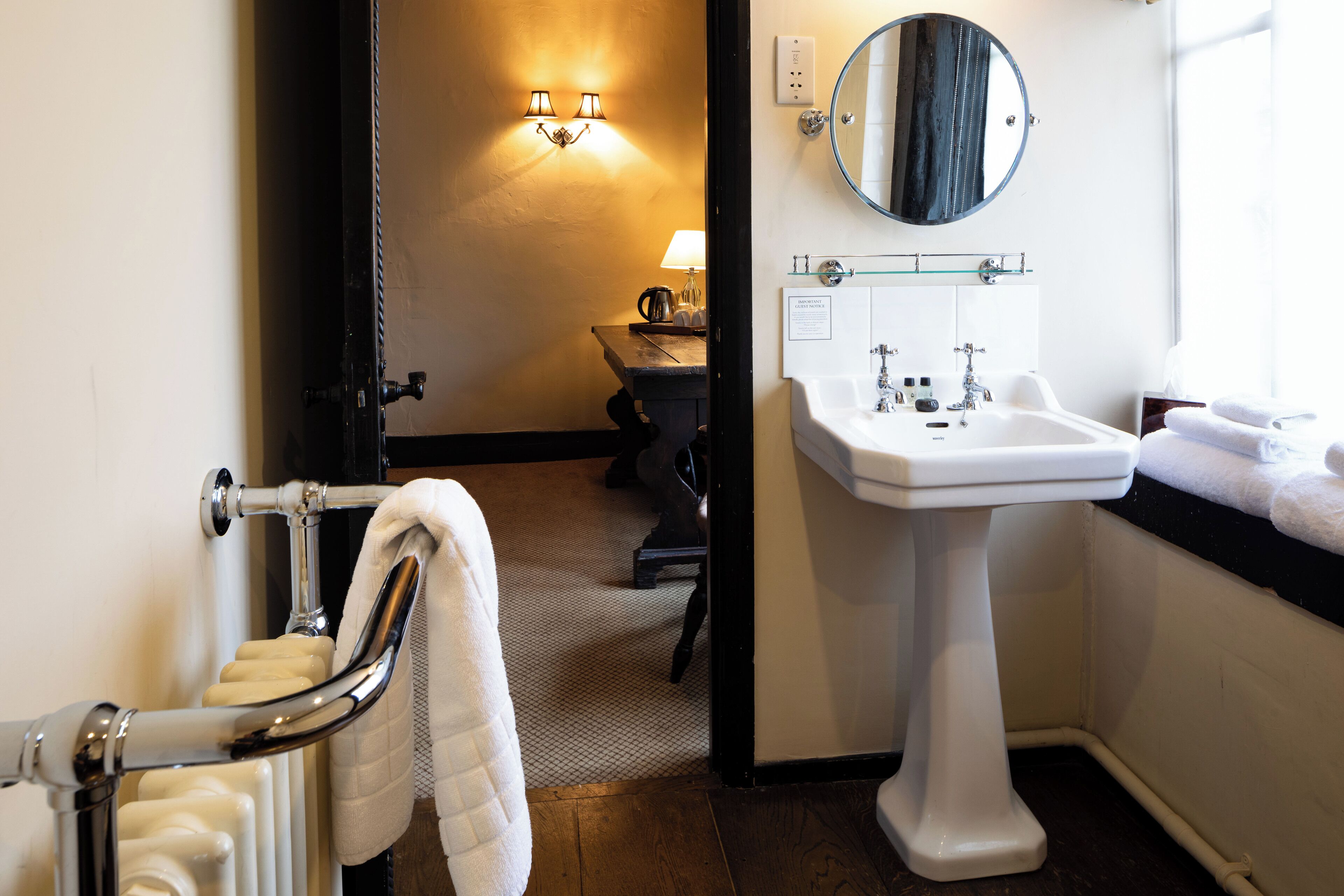 A bathroom with a white sink, a mirror, a towel rack, and a radiator.
