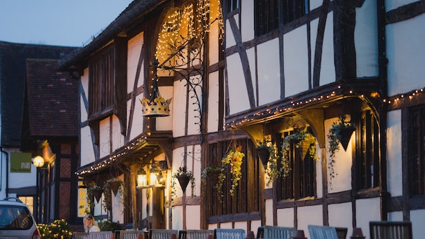 A traditional half-timbered building with outdoor seating and hanging plants. - The Crown Inn (Godalming)