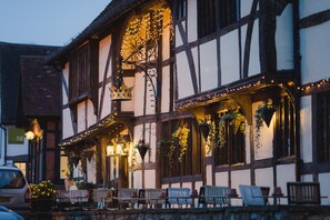 A traditional half-timbered building with outdoor seating and hanging plants.