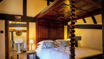 A traditional bedroom with a four-poster bed, wooden beams, and a classic design.