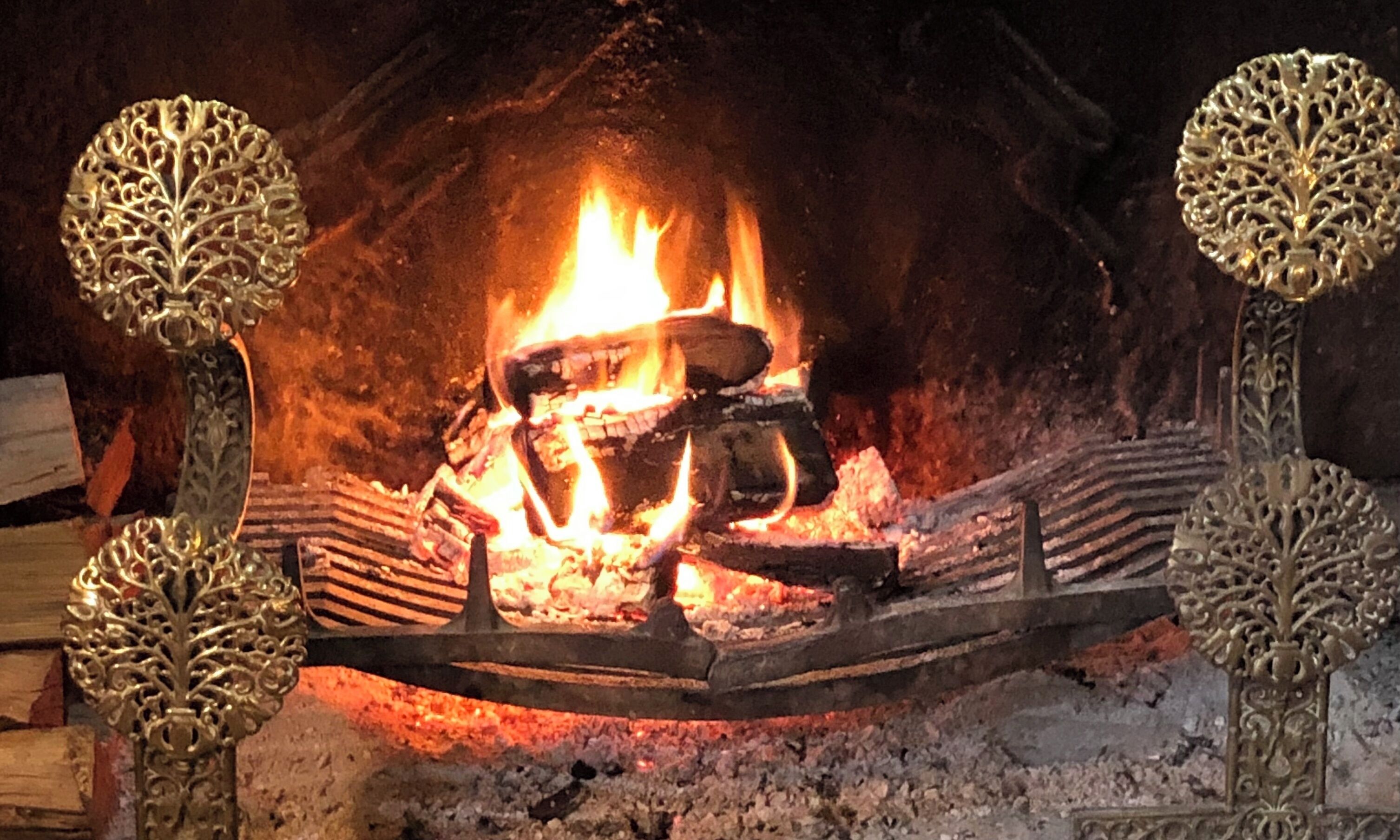 A fireplace with logs and a fire burning inside.