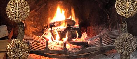 A fireplace with logs and a fire burning inside.