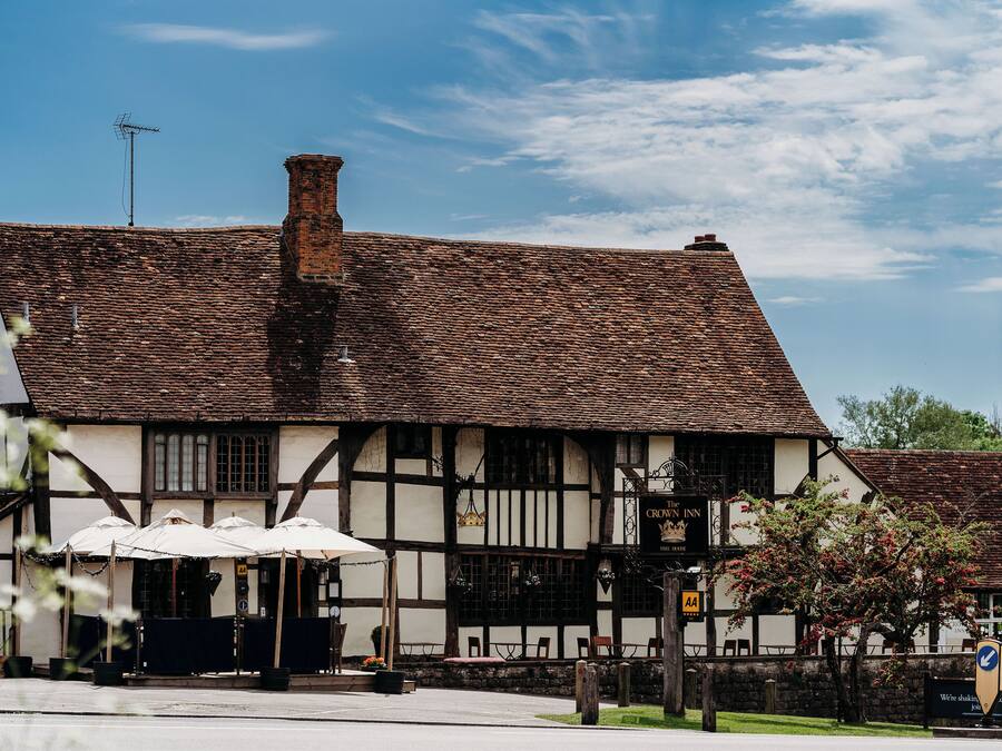 Un edificio de estilo Tudor tradicional con un techo empinado, numerosas ventanas y un letrero que indica que es un pub.