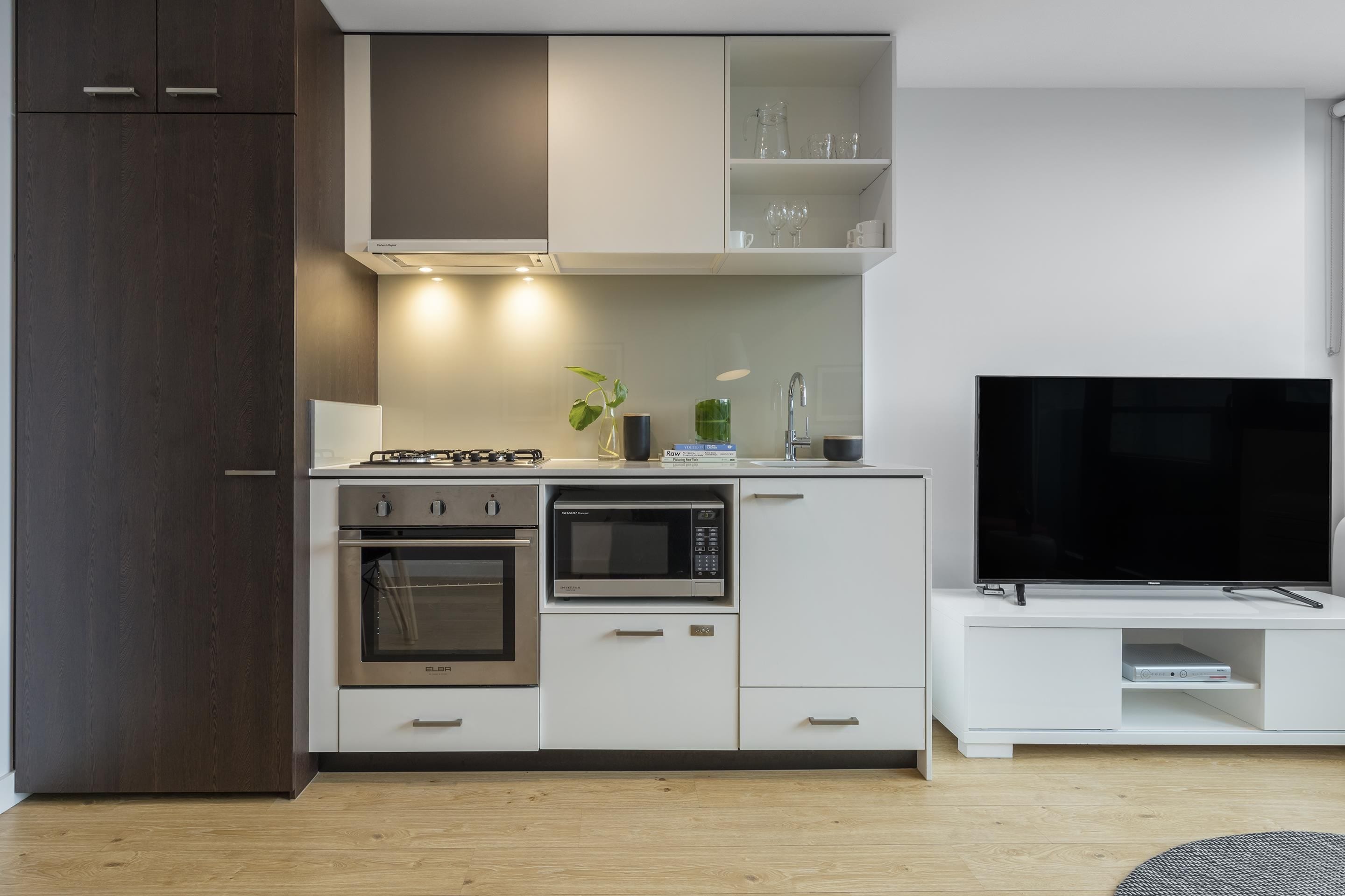 A modern kitchen with built-in appliances, a flat-screen TV, and a dining area.