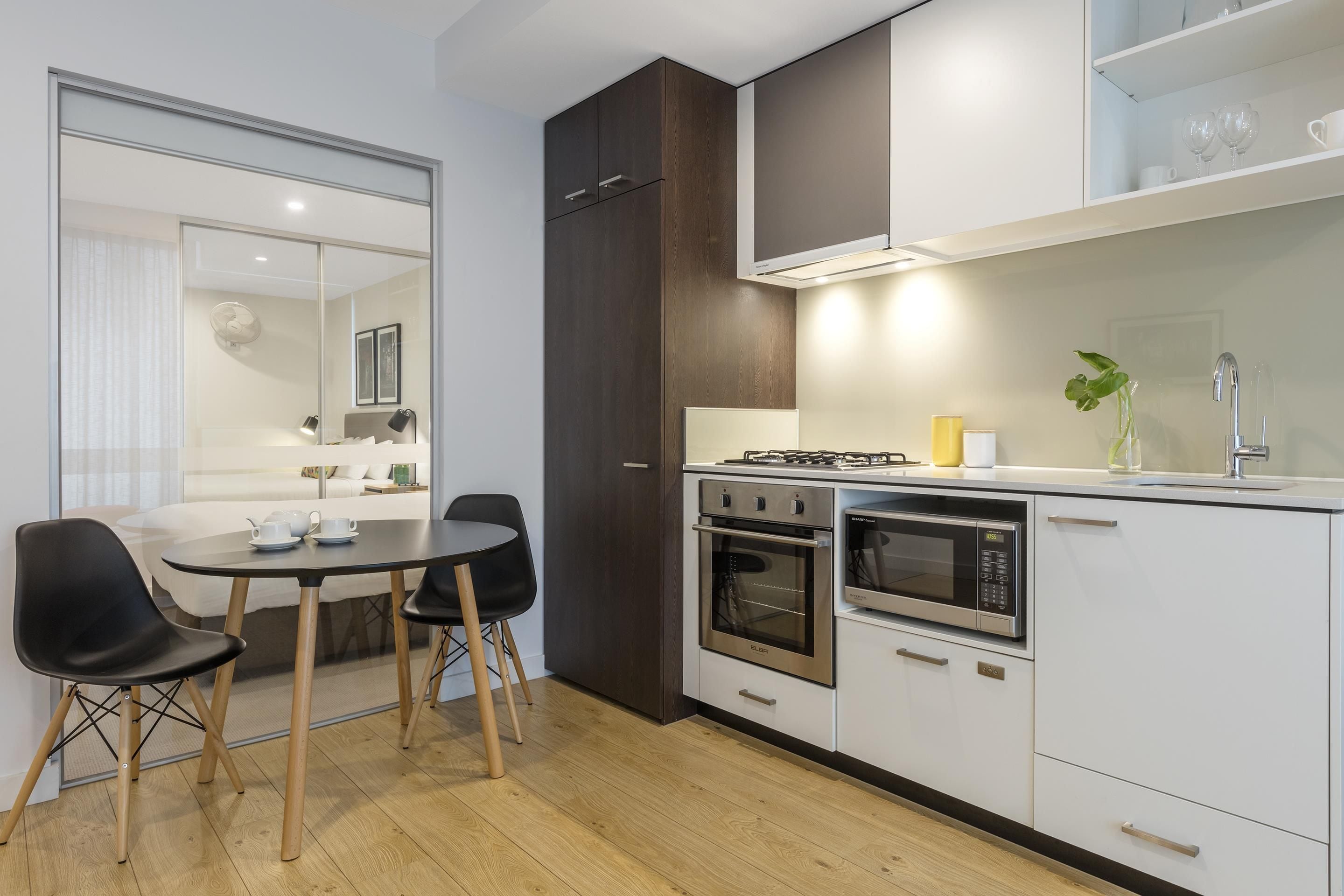 A modern kitchen with a dining area, including a table with chairs, a stove, oven, microwave, and cabinets.