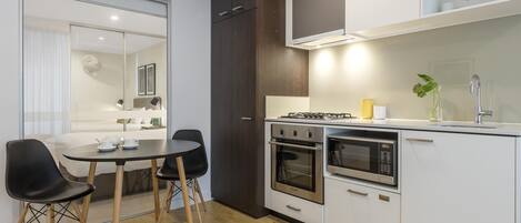 A modern kitchen with a dining area, including a table with chairs, a stove, oven, microwave, and cabinets.