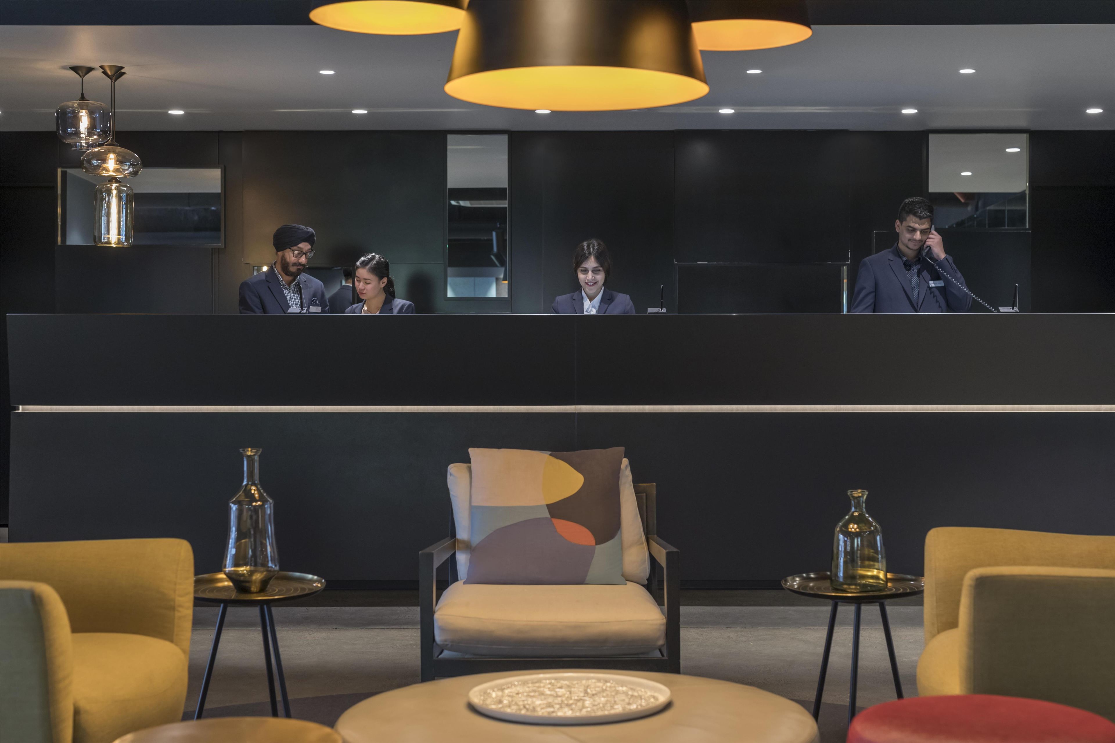 A modern hotel lobby with a reception desk, seating area, and contemporary decor.
