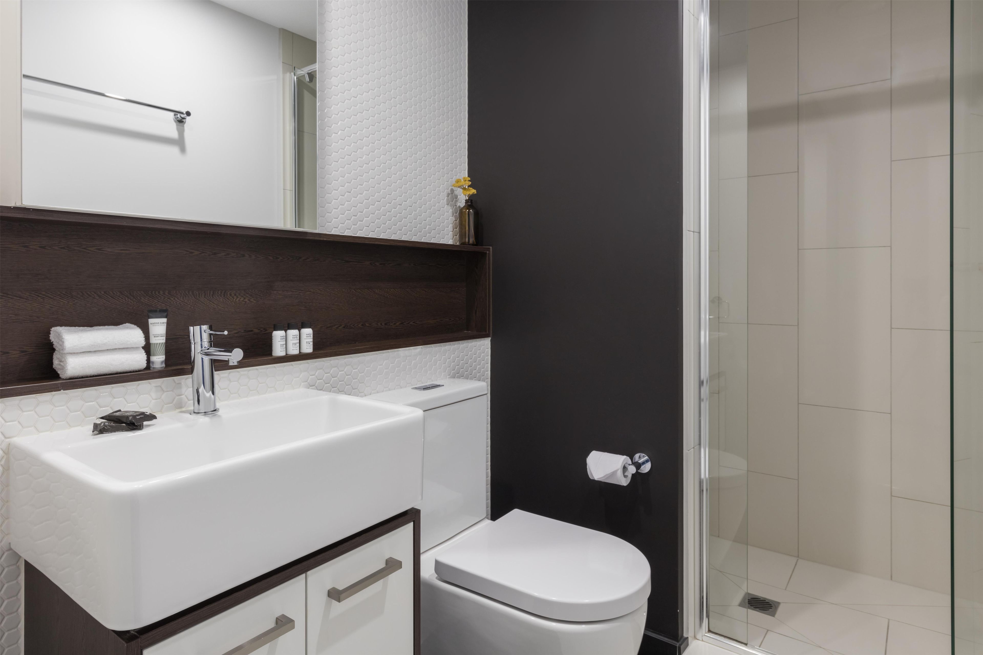 A modern bathroom with a white sink, a toilet, and a glass shower enclosure.