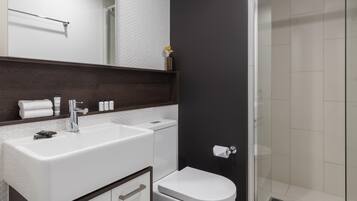 A modern bathroom with a white sink, a toilet, and a glass shower enclosure.