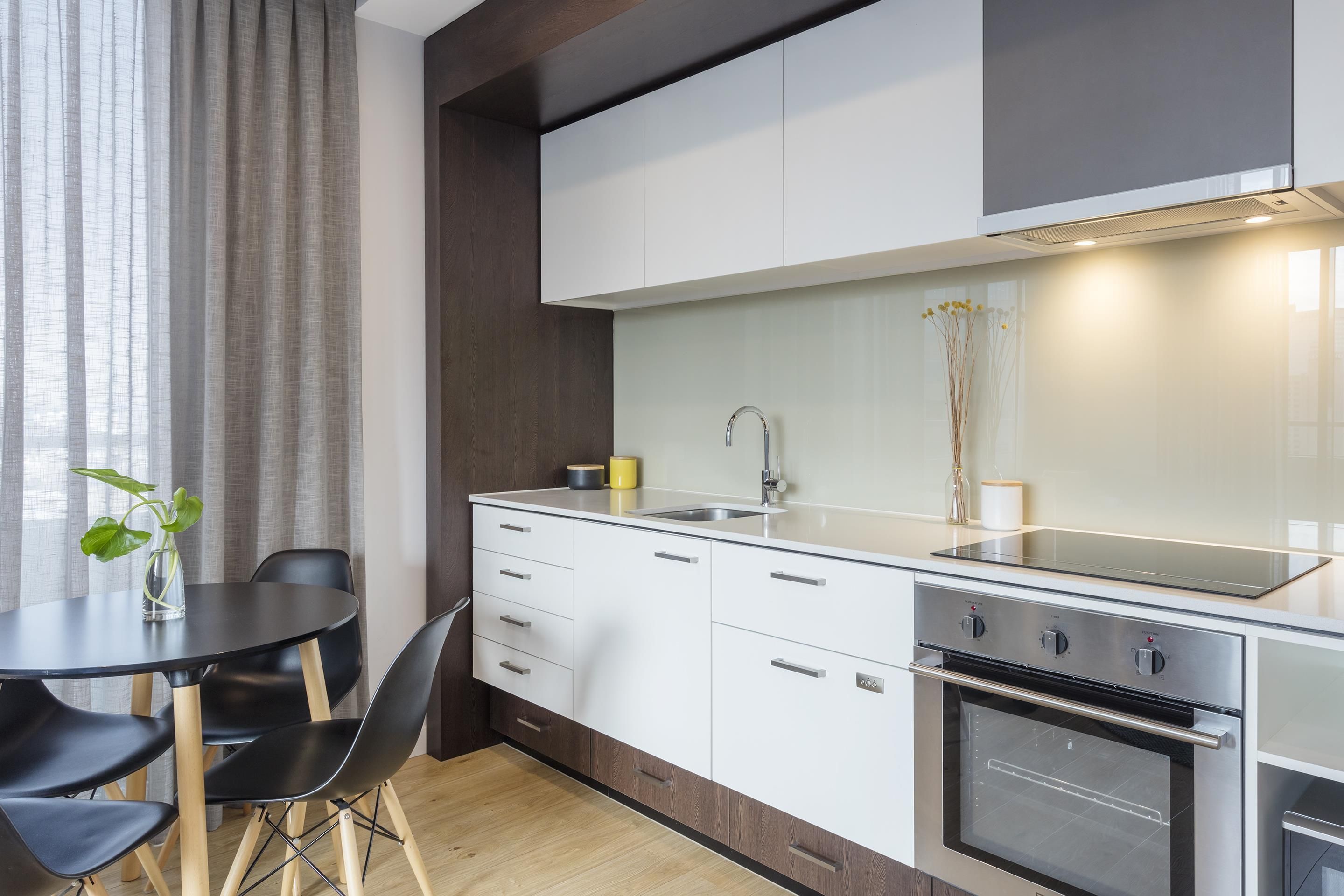 Una cocina moderna con comedor, que incluye una mesa redonda, sillas y un horno empotrado.