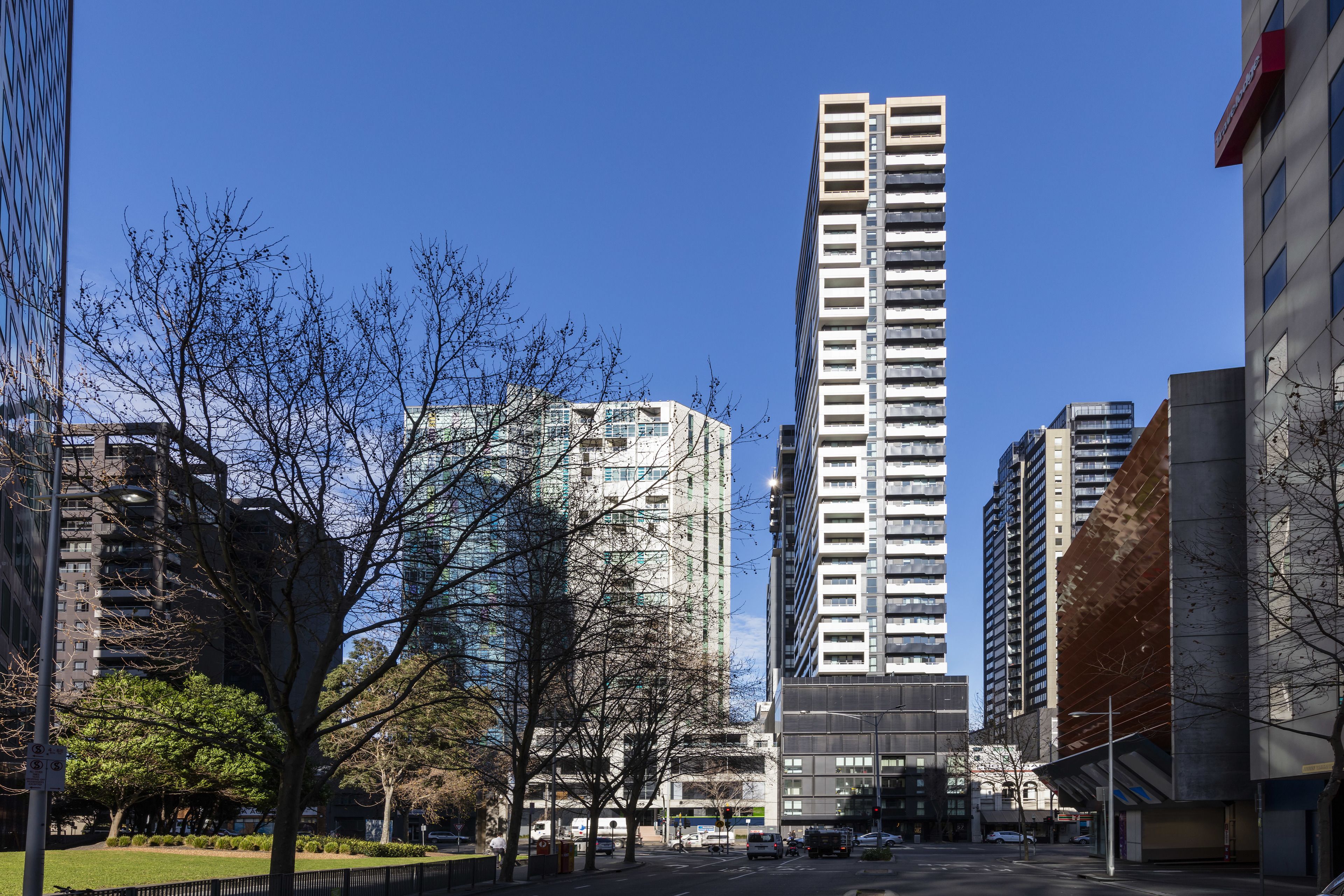 A tall building with a modern design, surrounded by trees and other buildings.