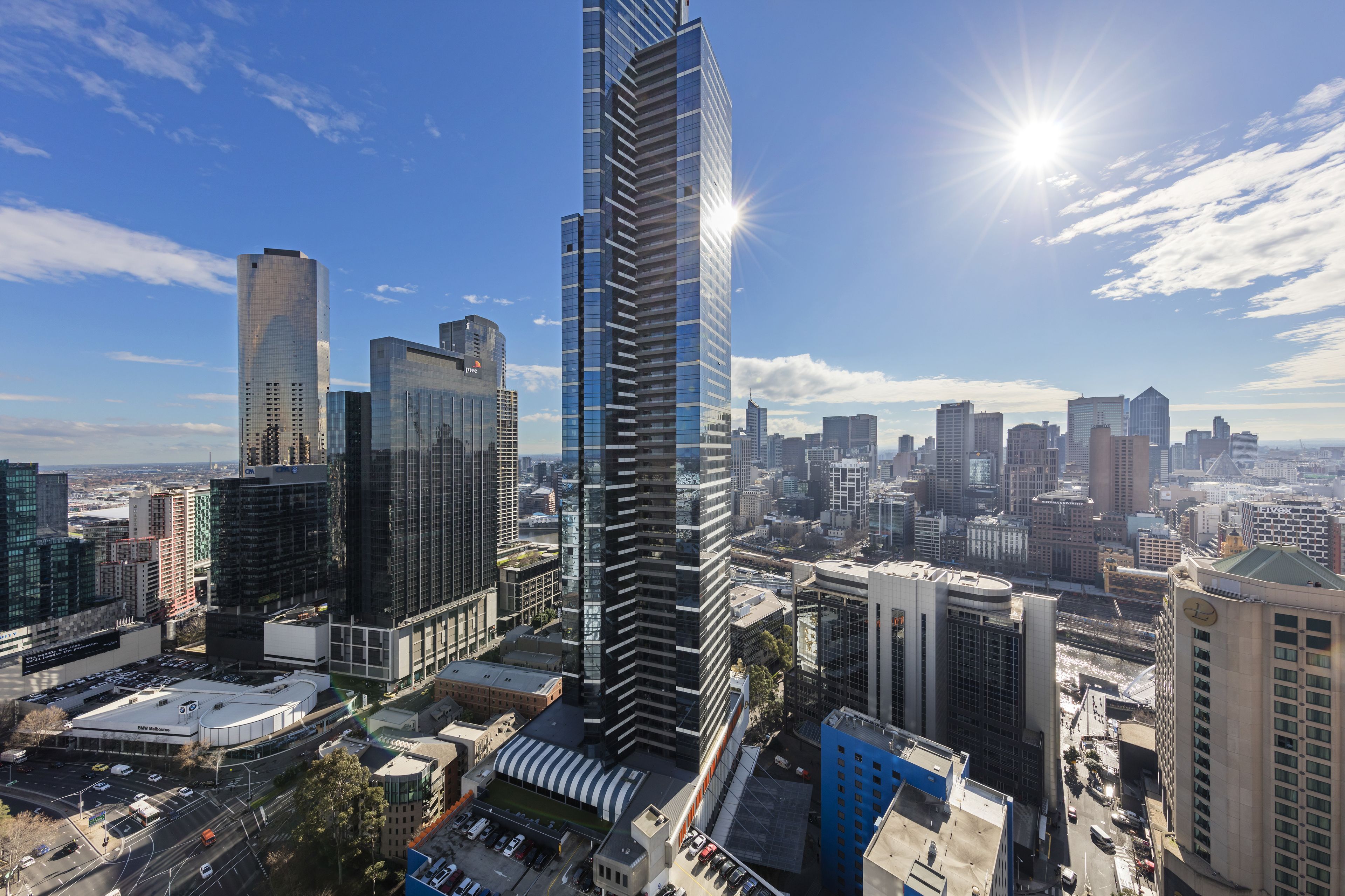 A high-rise building with a modern glass facade, surrounded by other skyscrapers in a cityscape.