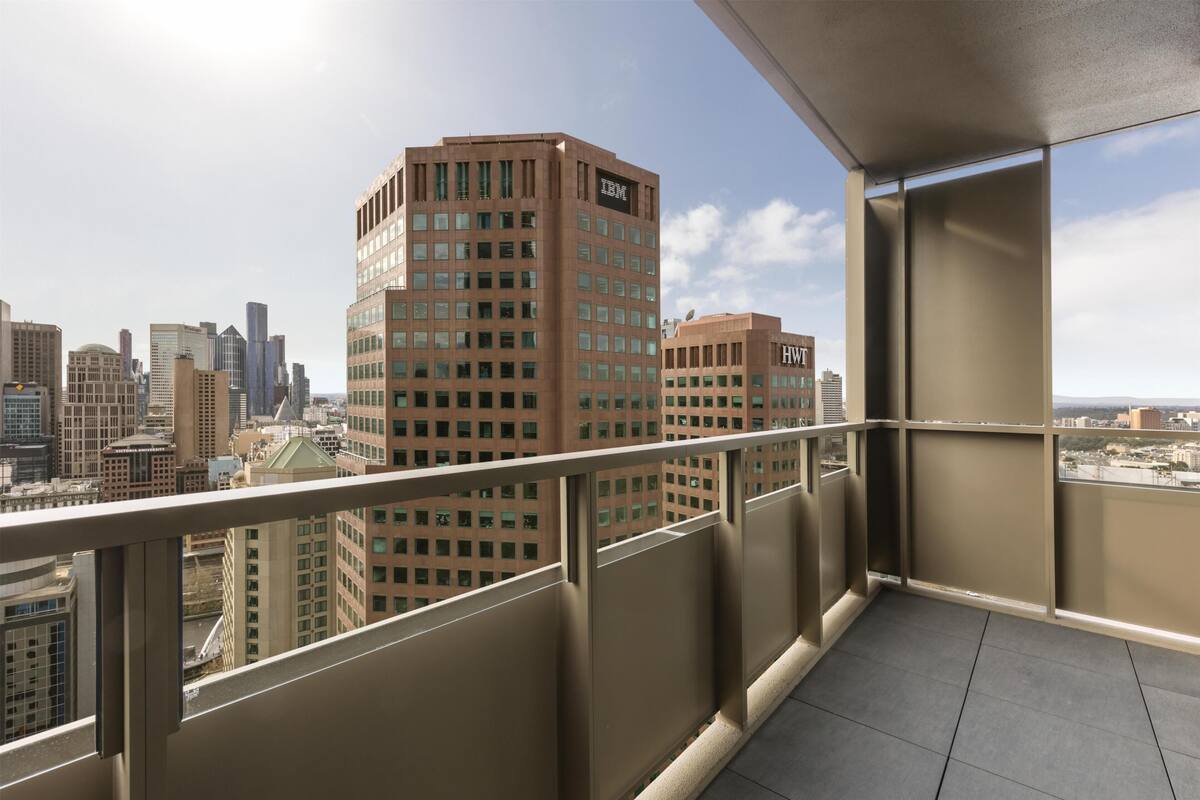 Un balcón con vista a un paisaje urbano, que incluye edificios altos con logotipos visibles.