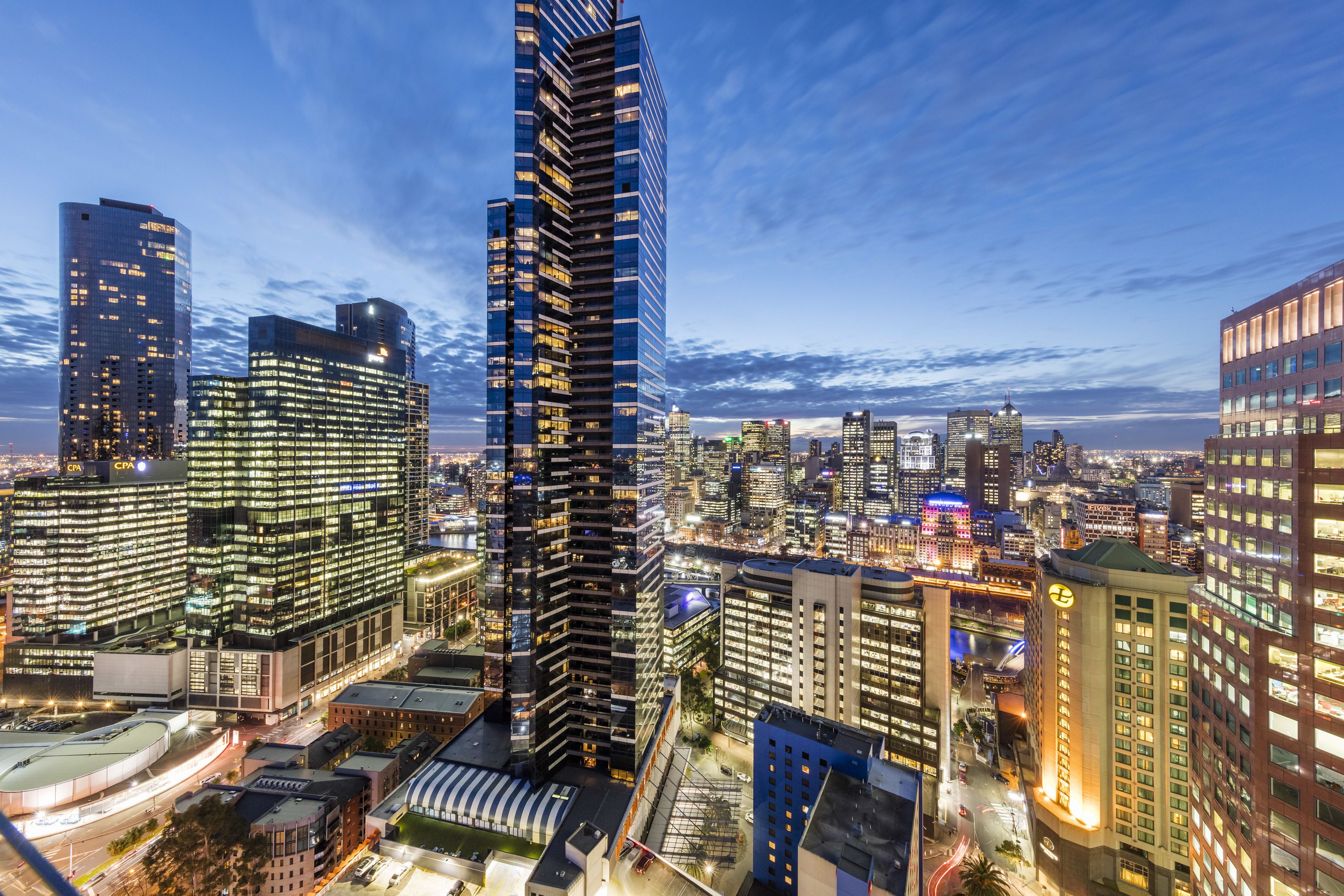 A high-rise building with a modern glass facade, surrounded by other tall buildings in a cityscape.
