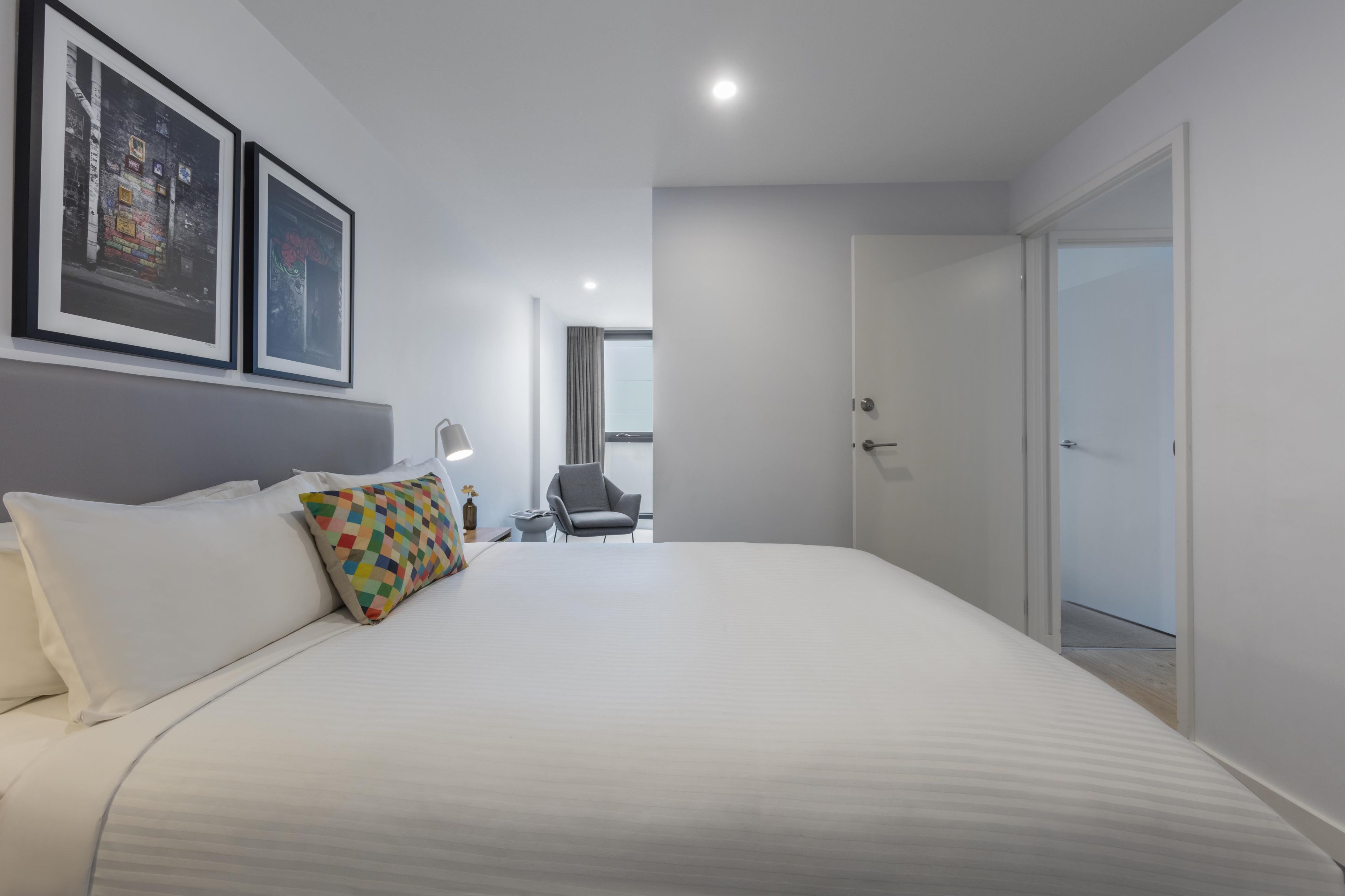 Ein Hotelzimmer mit einem großen Bett, einem Sessel, einem Schreibtisch und zwei gerahmten Bildern an der Wand.