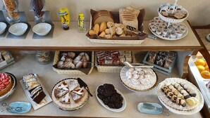 Ein Buffet mit verschiedenen Desserts und Gebäck, darunter Kuchen, Torten und Brot.