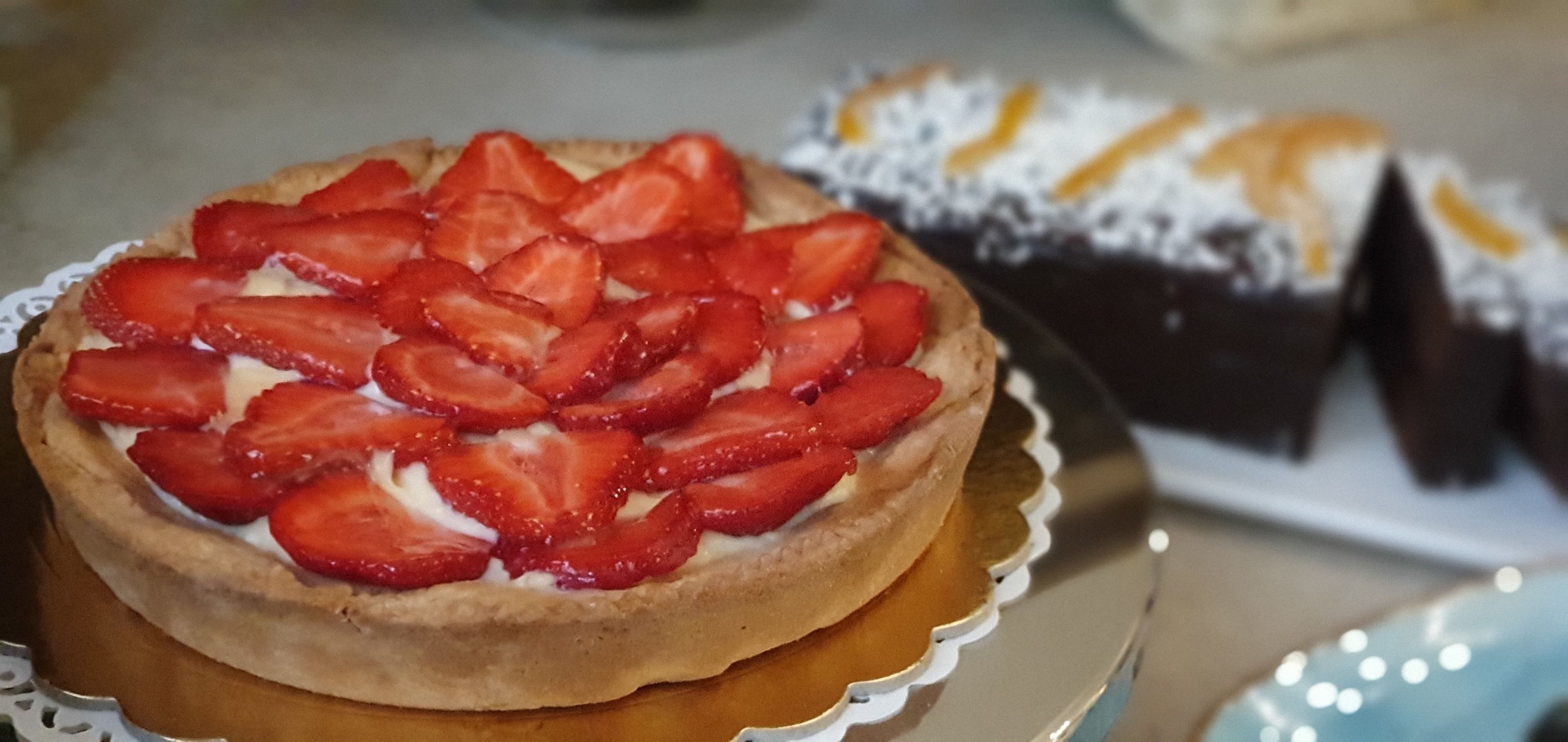 Ein Desserttörtchen mit Erdbeeren auf einem Teller.