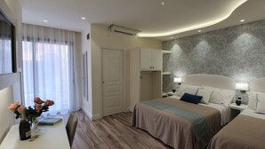 Ein Hotelzimmer mit zwei Betten, einem Schreibtisch mit Stuhl, einem Fenster mit Vorhängen und einer Wand mit Struktur.