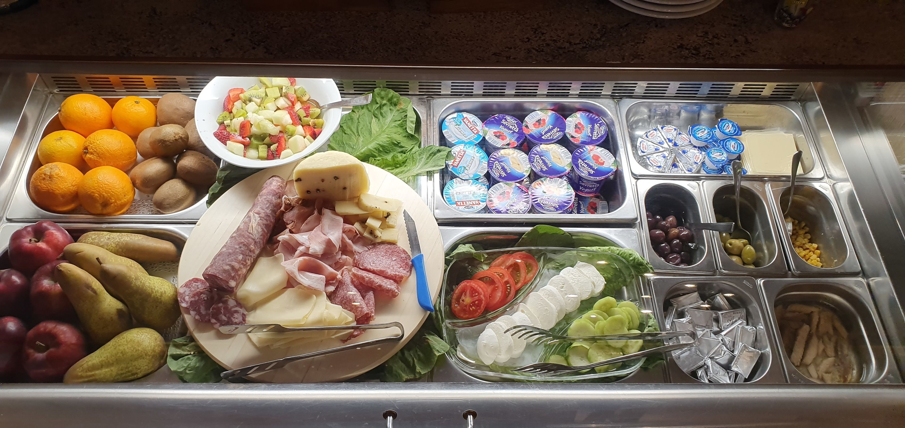 Un bufé con diversas opciones de comida, como frutas, quesos, carnes y verduras.