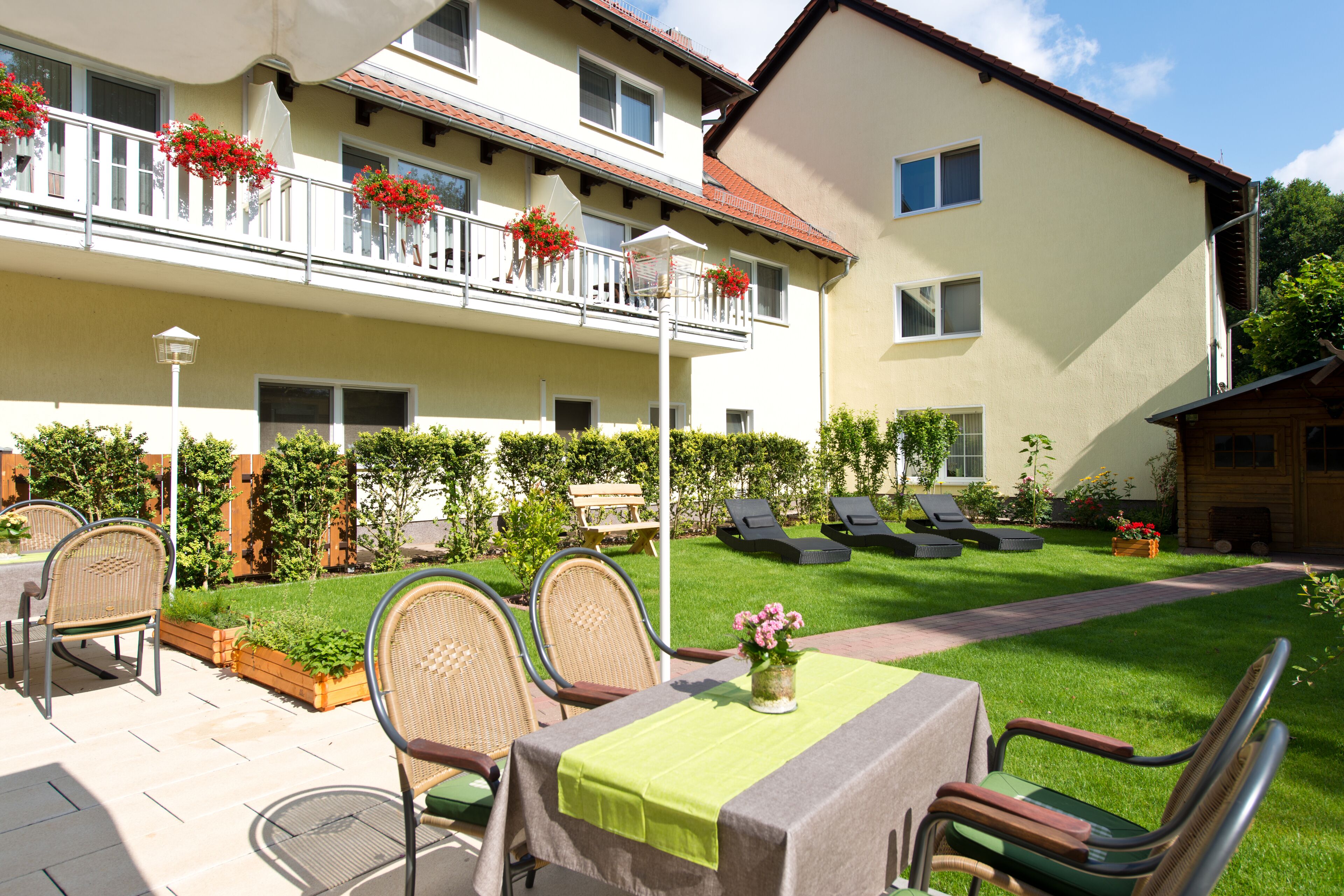 A courtyard with outdoor seating, a table with a tablecloth, and a flower vase.