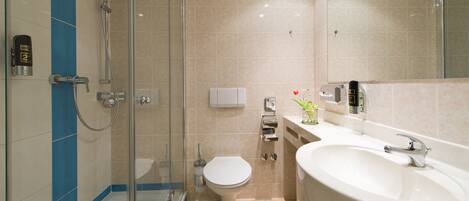 A modern bathroom with a glass-enclosed shower, a white toilet, and a large sink.