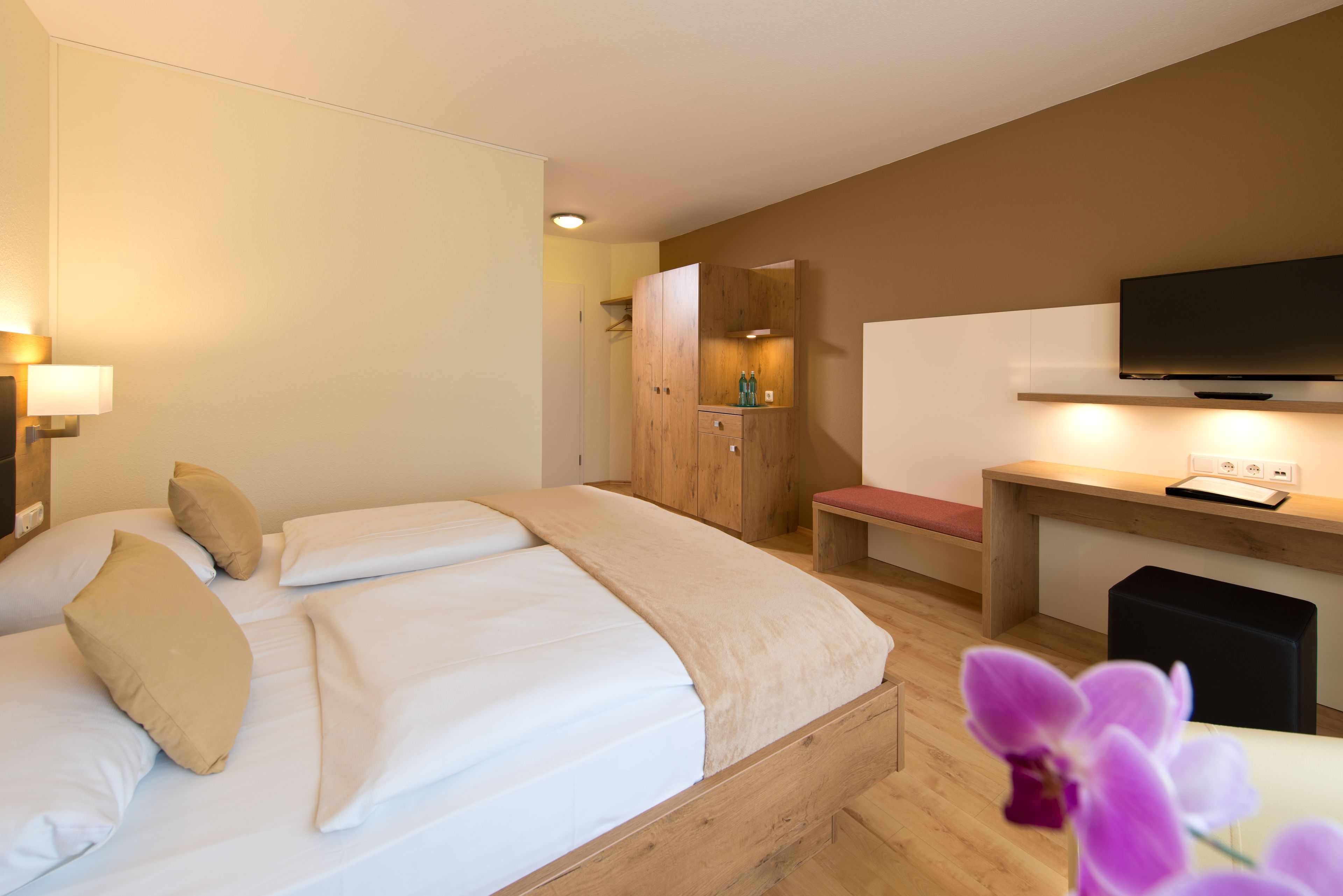 A hotel room with a bed, a desk, a television, and a wardrobe.