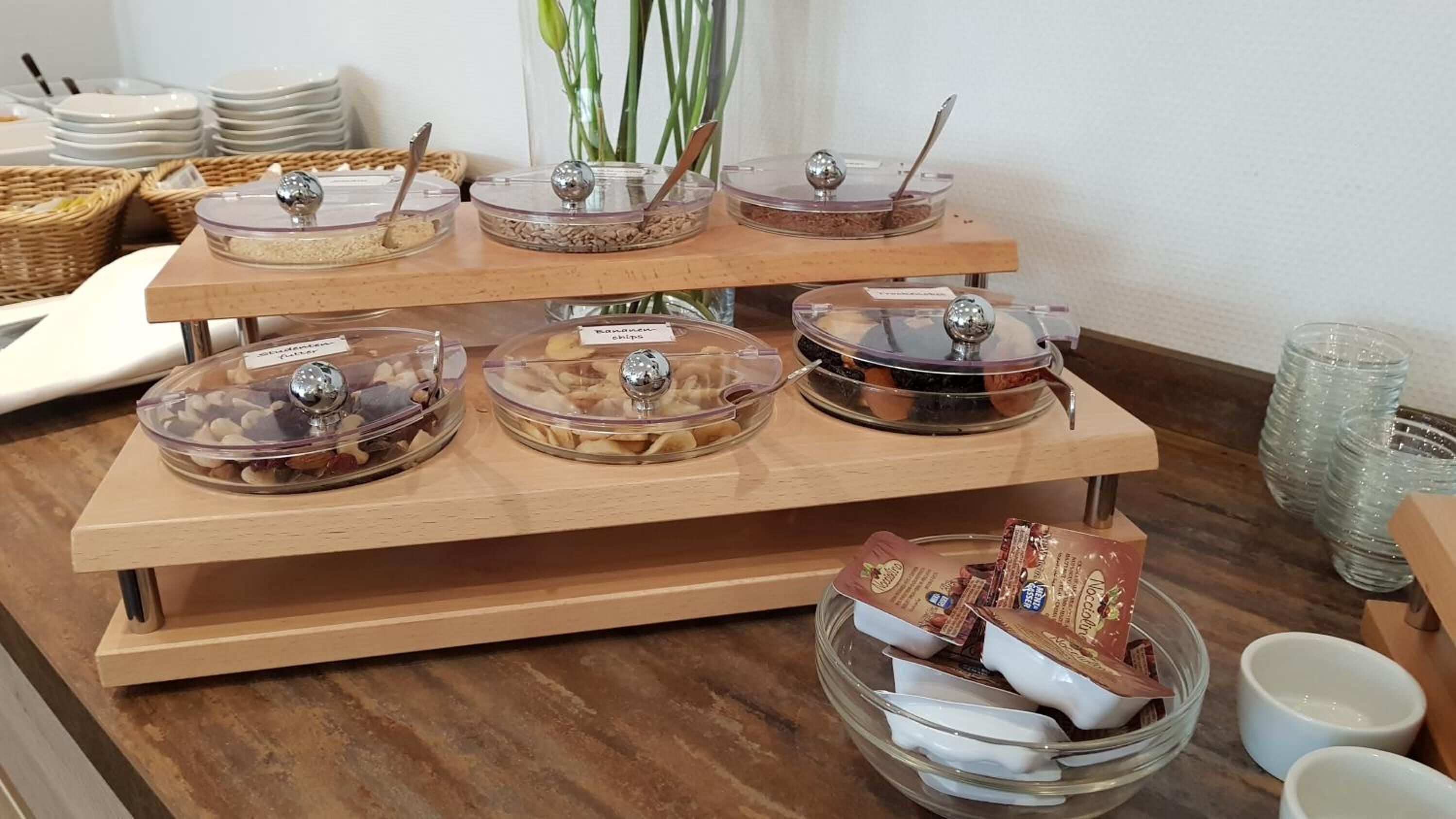 A buffet setup with various food items in clear containers, including chips and possibly other snacks.
