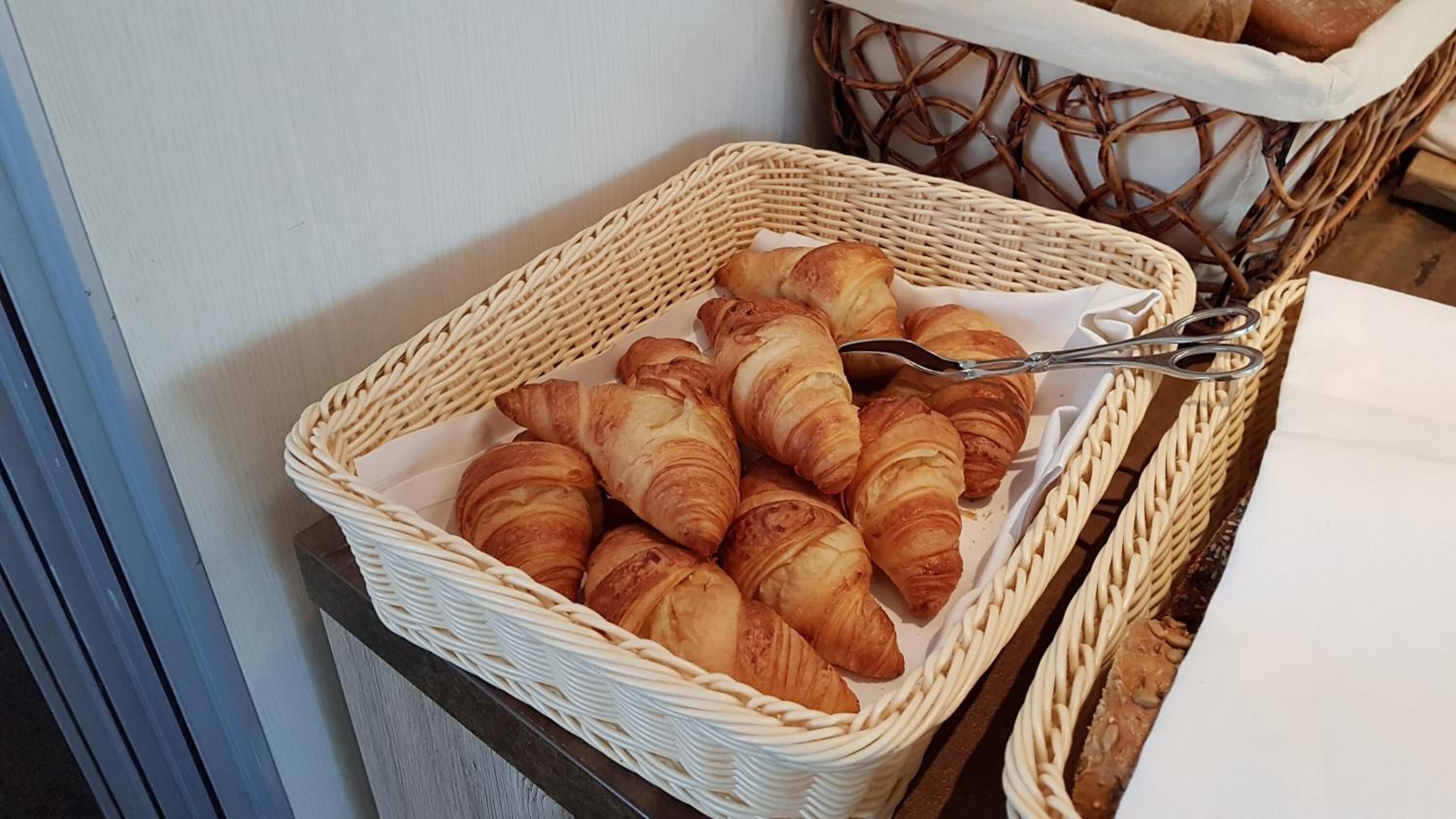 Un cesto di vimini pieno di croissant su un tavolo.