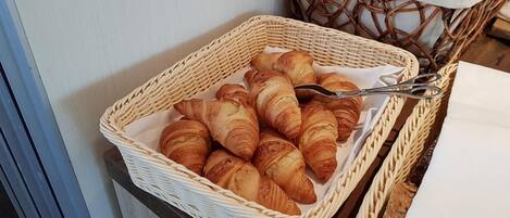 Un cesto di vimini pieno di croissant su un tavolo.