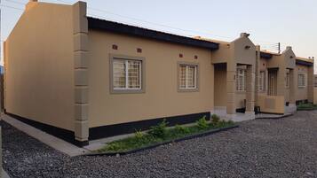 A row of beige buildings with multiple windows and a gravel driveway.