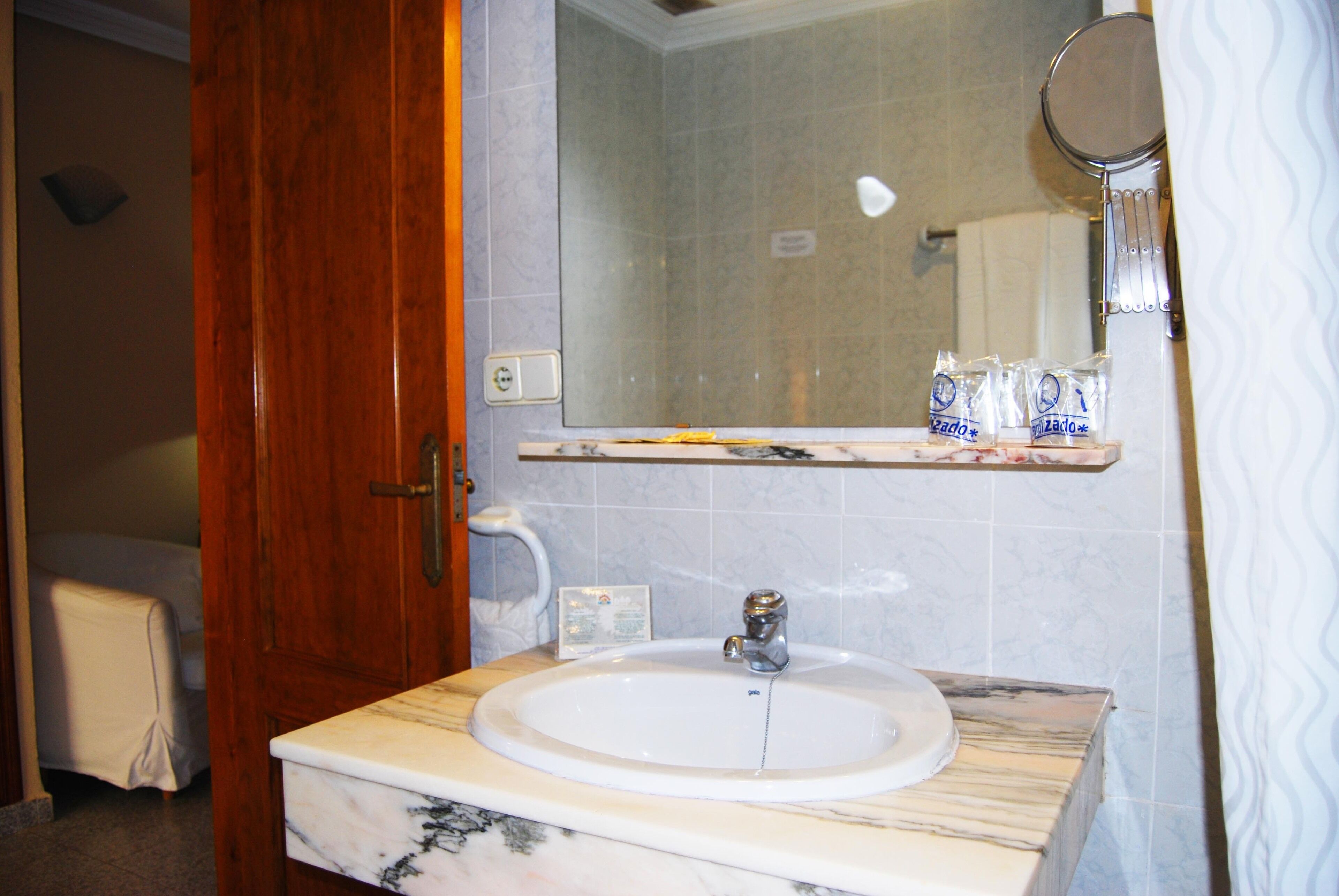 Un baño con lavamanos de mármol, espejo y toallero.