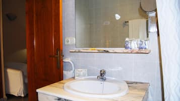 Un baño con lavamanos de mármol, espejo y toallero.