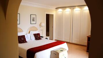 A bedroom with a bed, bedside table, lamp, wardrobe, and a small cabinet.