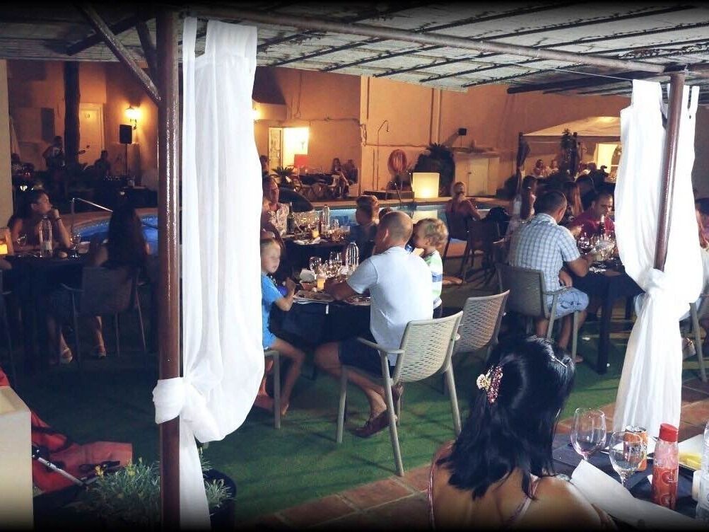 An outdoor dining area with tables and chairs, surrounded by white drapes.