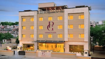 A hotel with a prominent 'Grand Plaza' sign, multiple windows, and a visible entrance with a reception desk.