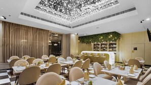 A restaurant with tables set for dining, a bar area, and a chandelier. - Grand Plaza Jammu (Jammu)