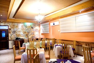 A restaurant with stone walls, wooden ceiling beams, and tables set for dining.