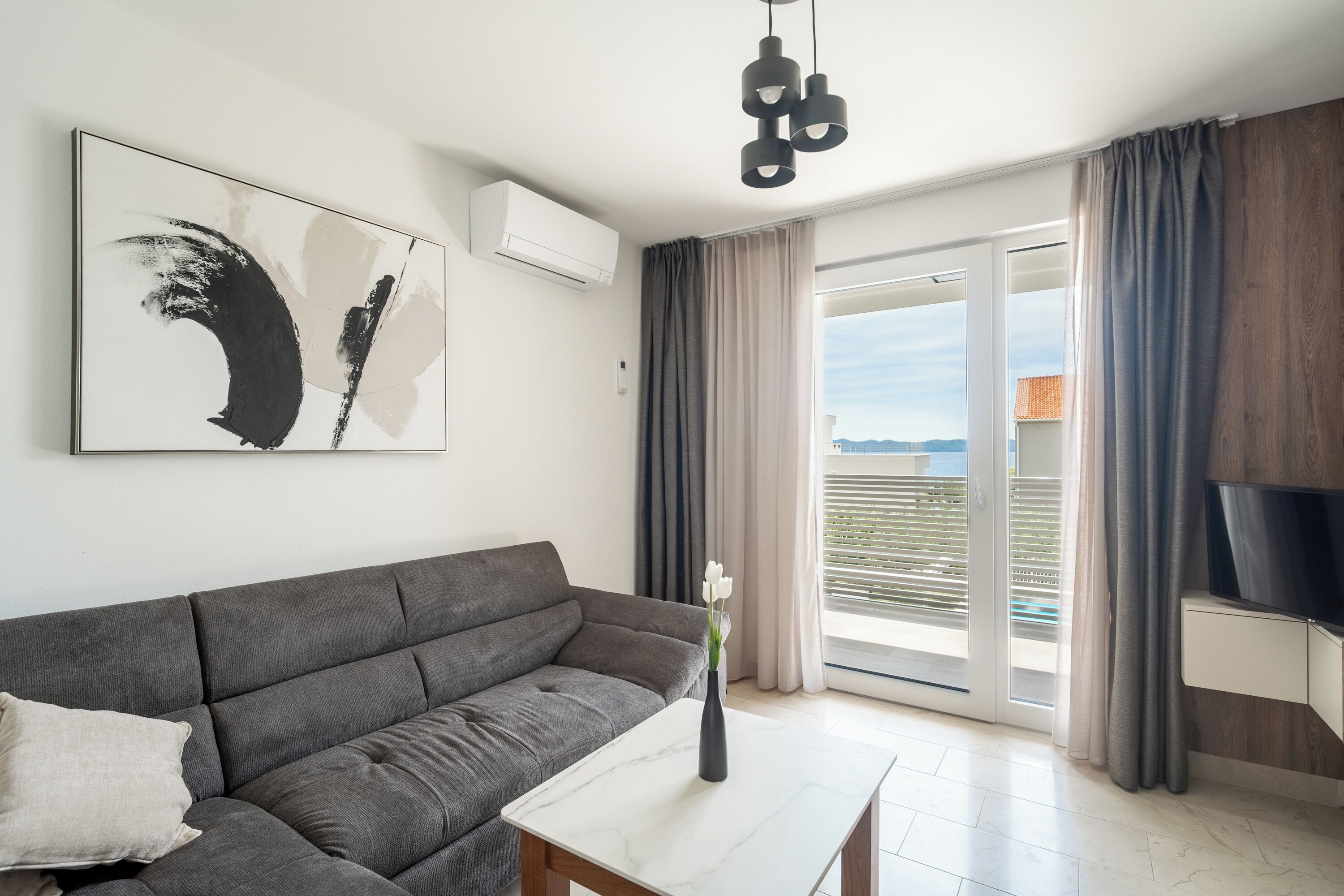 A modern living room with a grey sofa, a white coffee table, and a large abstract painting.