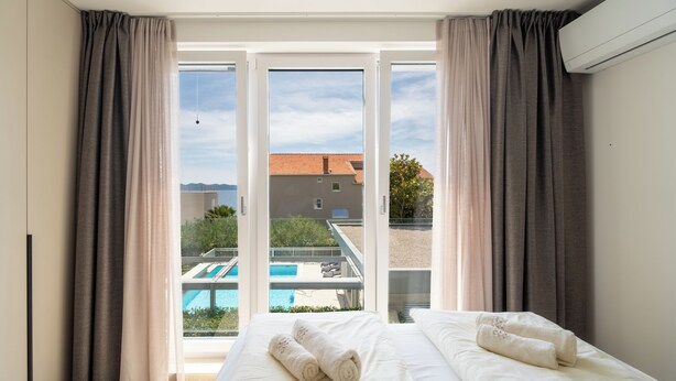 Une chambre d’hôtel avec un lit, deux serviettes et une vue sur une piscine extérieure.