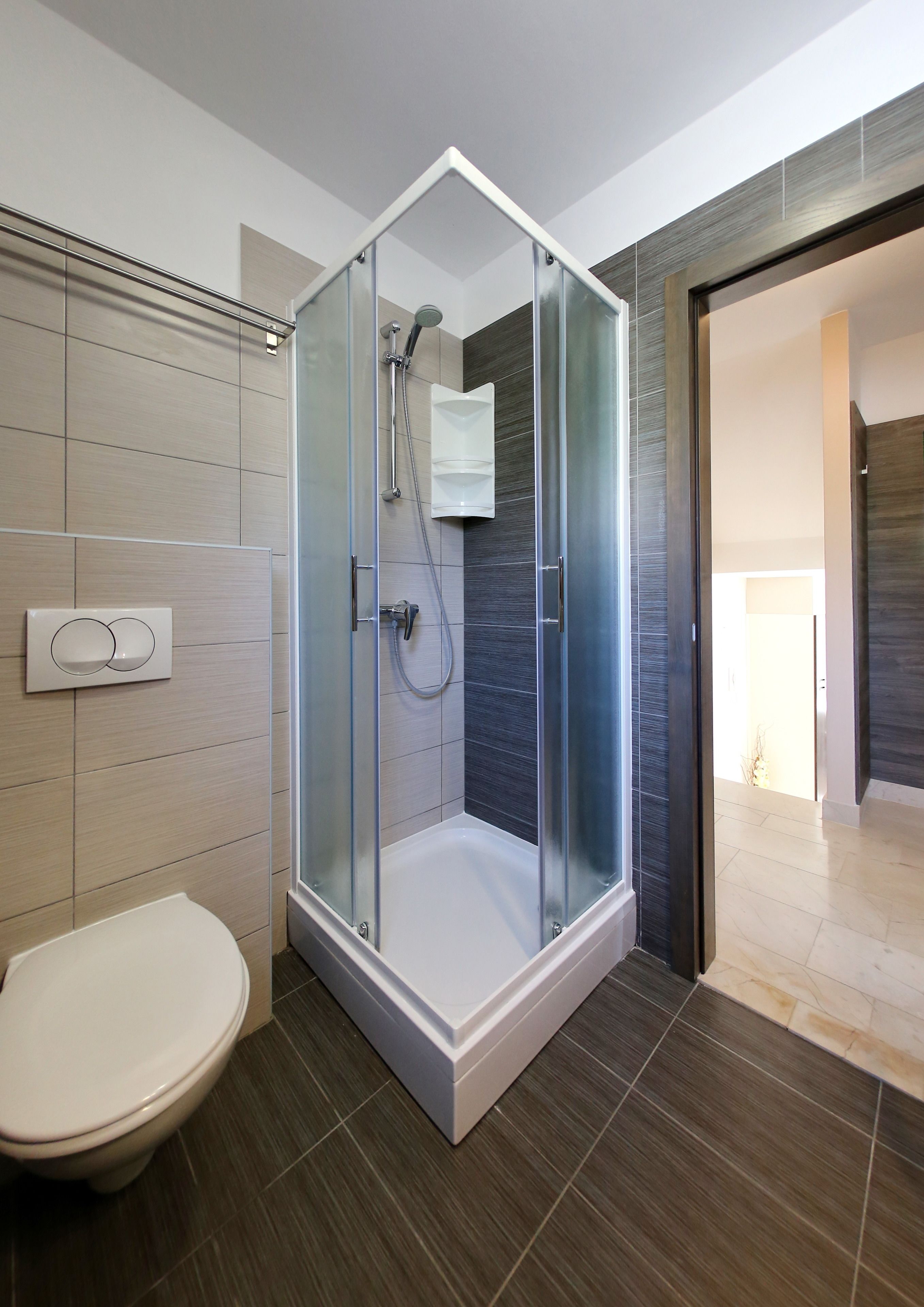 A modern bathroom with a glass-enclosed shower, a toilet, and a bathtub.