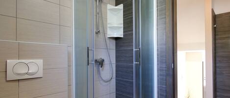 A modern bathroom with a glass-enclosed shower, a toilet, and a bathtub.