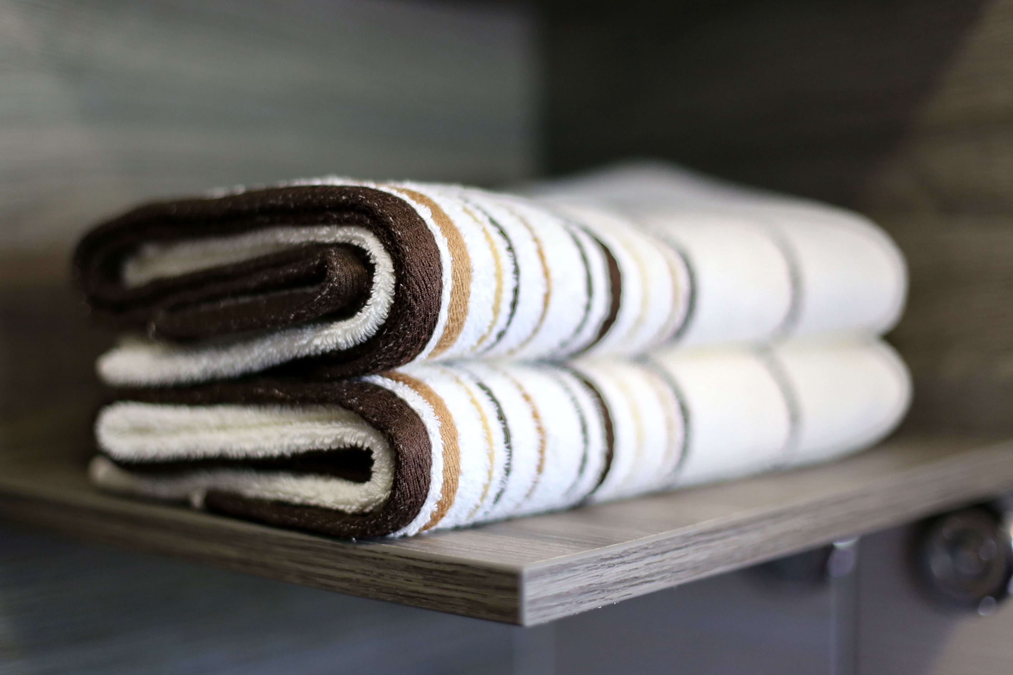 A stack of folded towels on a wooden shelf.