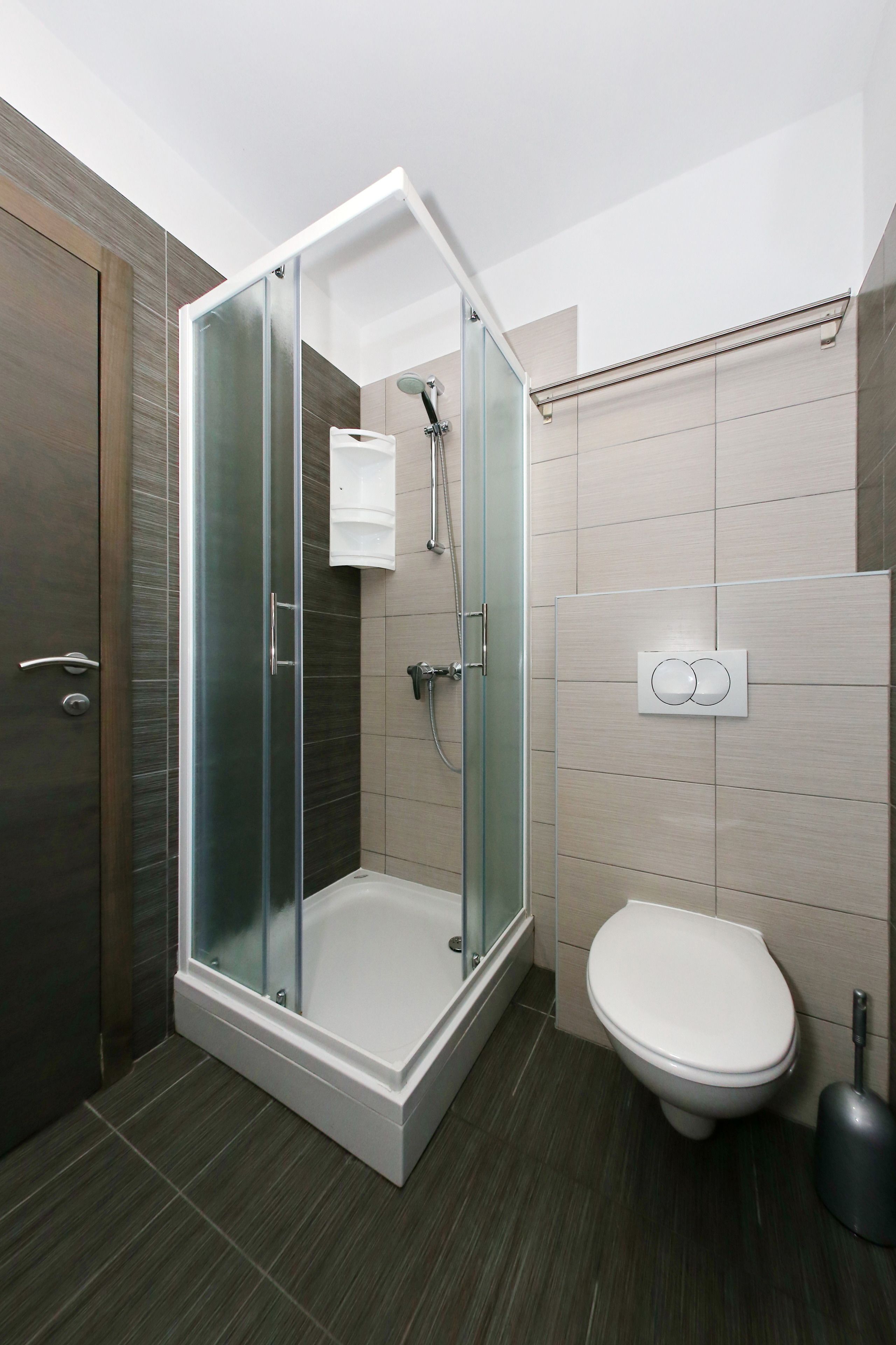 Een moderne badkamer met een douchecabine van glas, een toilet en een wastafel.