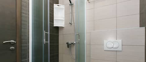 Een moderne badkamer met een douchecabine van glas, een toilet en een wastafel.