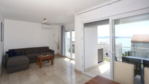 Un salon moderne avec un canapé, une table basse et un balcon offrant une vue sur la mer.
