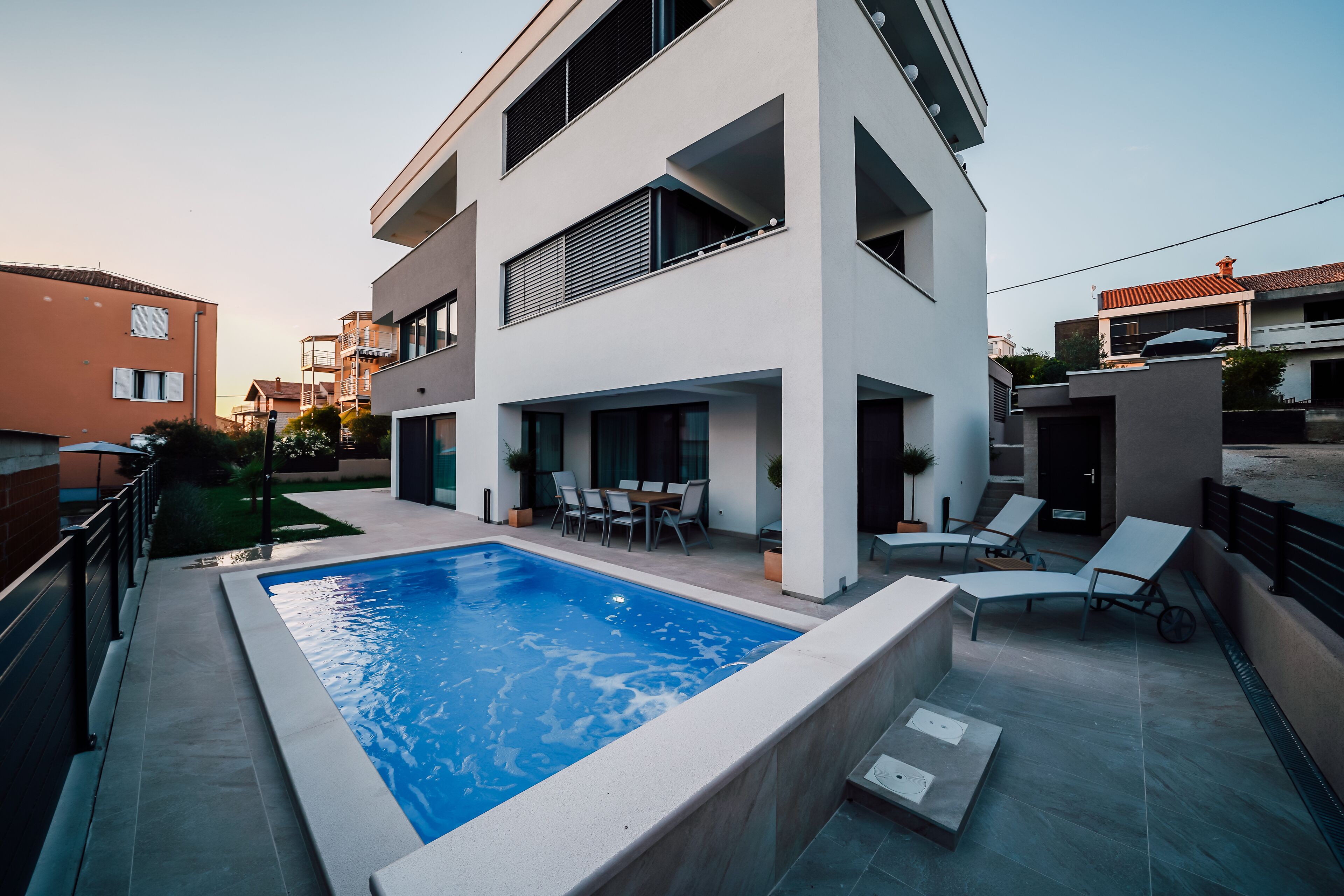 Uma casa moderna de dois andares com piscina, área de estar ao ar livre e varanda.