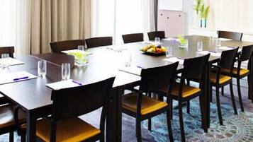 Ein Konferenzraum mit rundem Tisch, Stühlen und Obstschale.