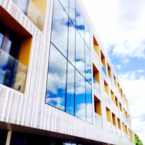 A modern building with a glass facade, geometric window patterns, and a clear sky view. - Hotel von Kraemer (Uppsala)