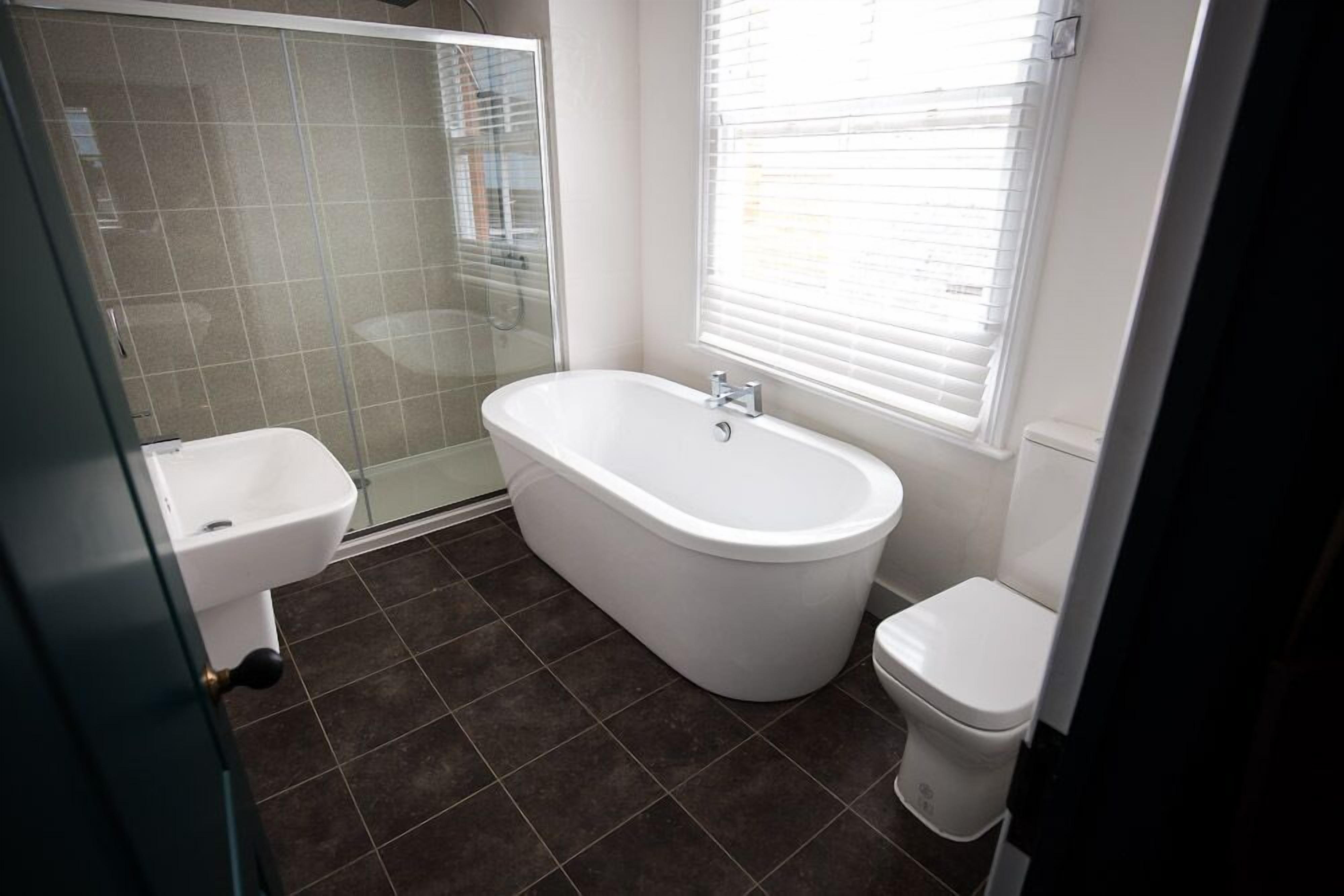 Une salle de bain équipée d’une baignoire, de toilettes et d’une douche à parois de verre.